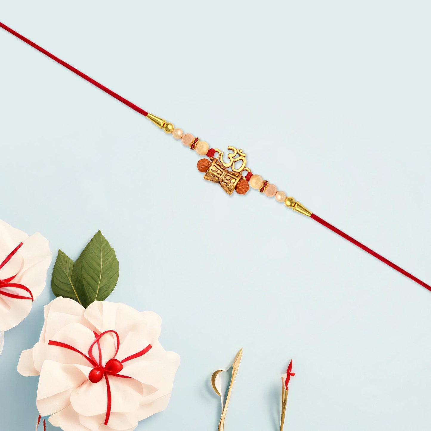 Close-up showing intricate golden charm and pearl beads on vibrant red thread Rakhi.