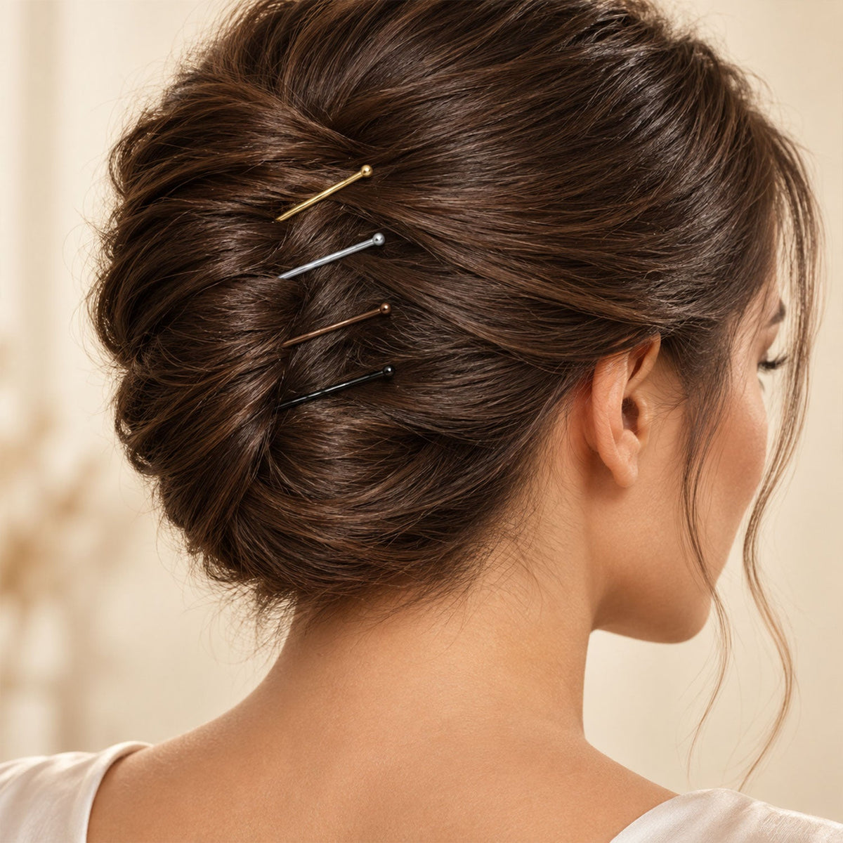 A woman's dark brown hair bun is styled with gold, silver, brown, and black bobby pins.