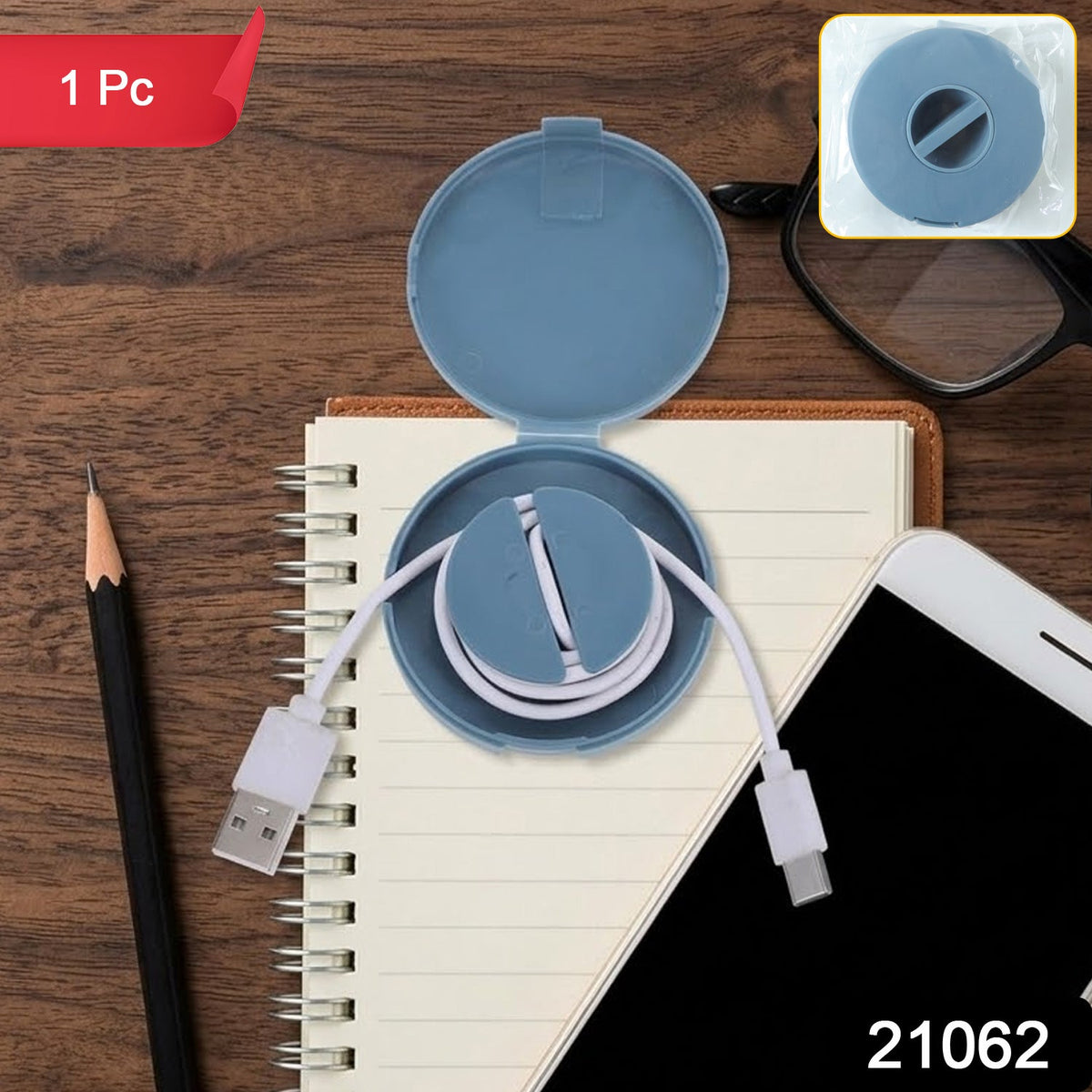 An open blue cable winder case with a white charging cable sits on a notebook next to a phone and pencil.