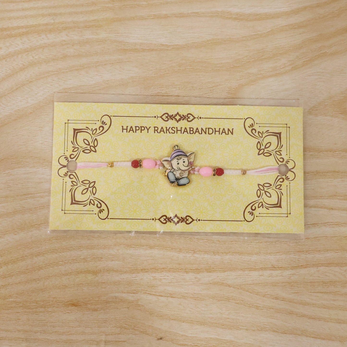 Festive Ganesha Rakhi with pink and red beads for Raksha Bandhan