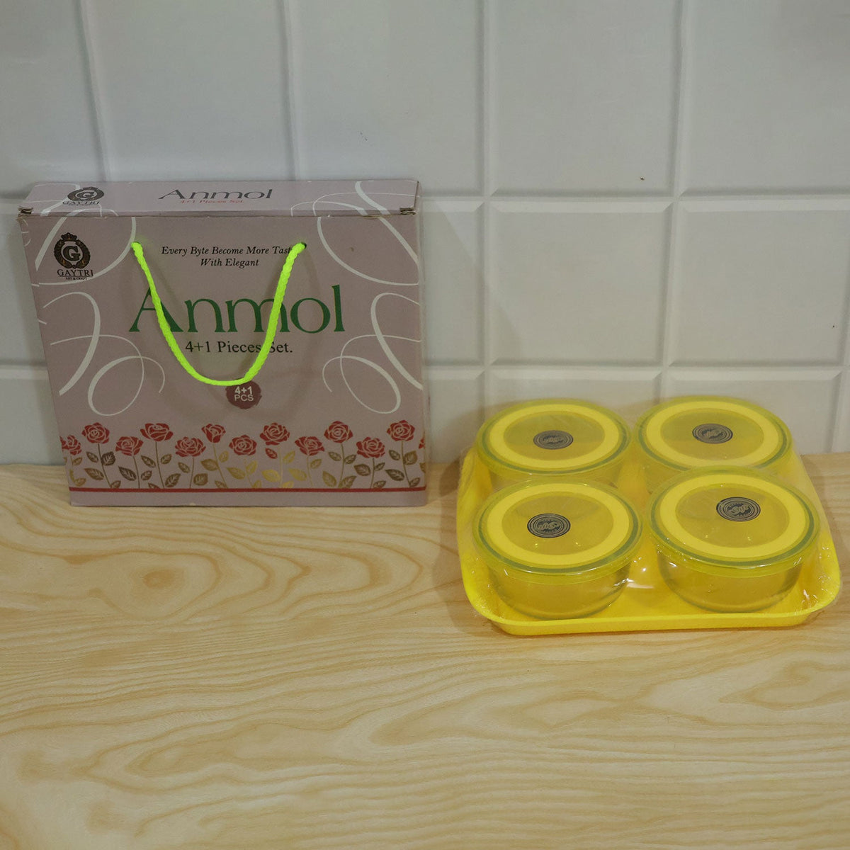 Four glass bowls with yellow lids on a tray, next to a gift box on a wooden surface.
