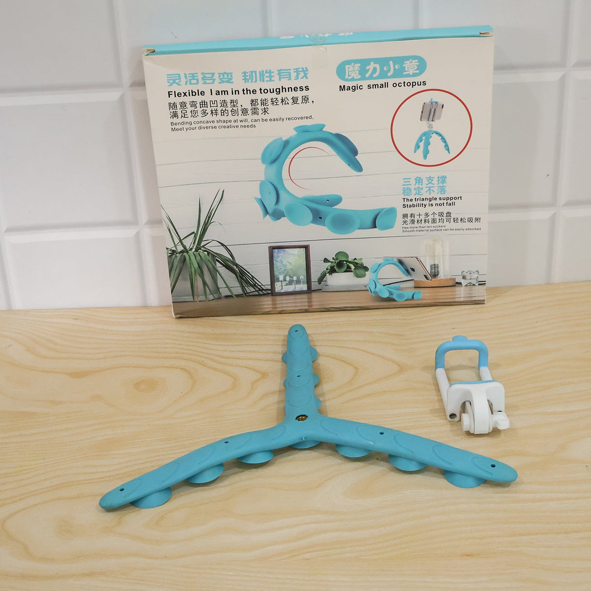 The blue flexible tripod base and white phone holder detached, with the product packaging box in the background.