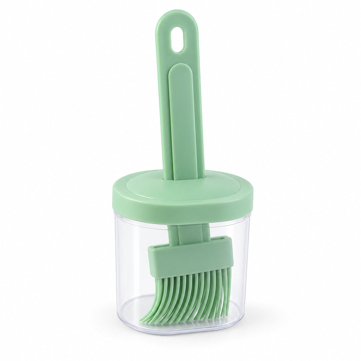A green silicone basting brush with a long handle stored vertically inside a clear cylindrical container with a matching