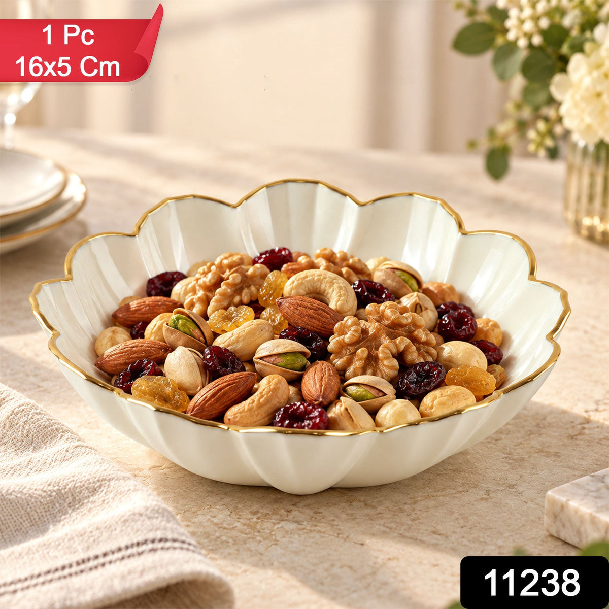 White ceramic scalloped bowl with a gold rim filled with mixed nuts and dried fruits on a light table. – view 2