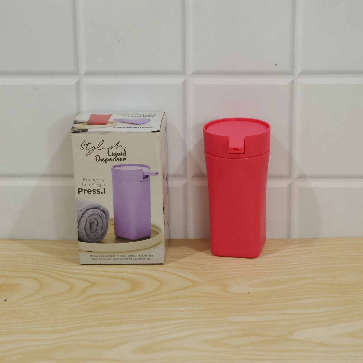 Coral pink liquid soap dispenser bottle on a white surface with soft lighting