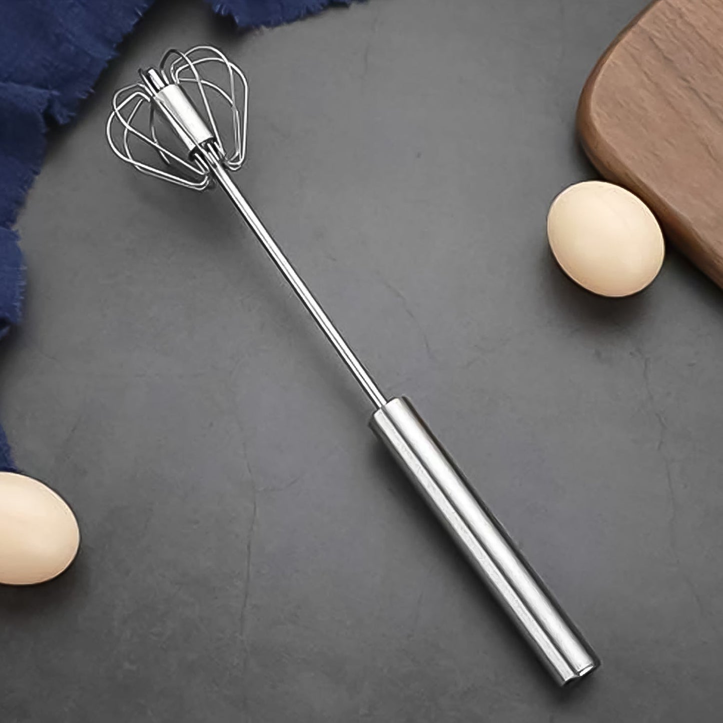 Stainless steel egg whisk with a hand push rotary design on a clean background.