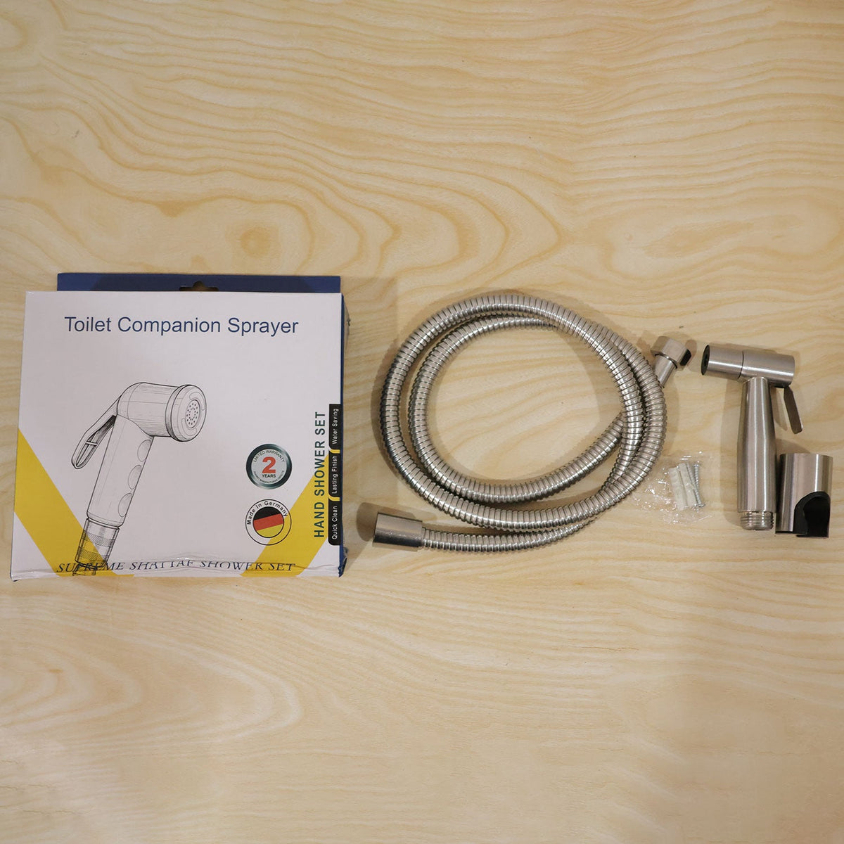 A product box labeled "Toilet Companion Sprayer" is displayed next to the brushed steel bidet sprayer, coiled hose, wall