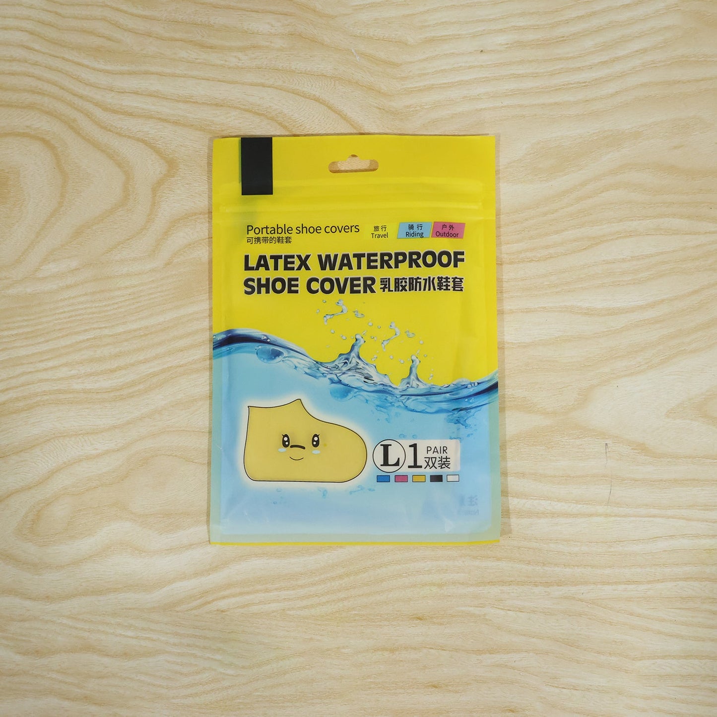 A yellow and blue package for "Latex Waterproof Shoe Cover" with a cartoon shoe graphic rests on a light wood surface.