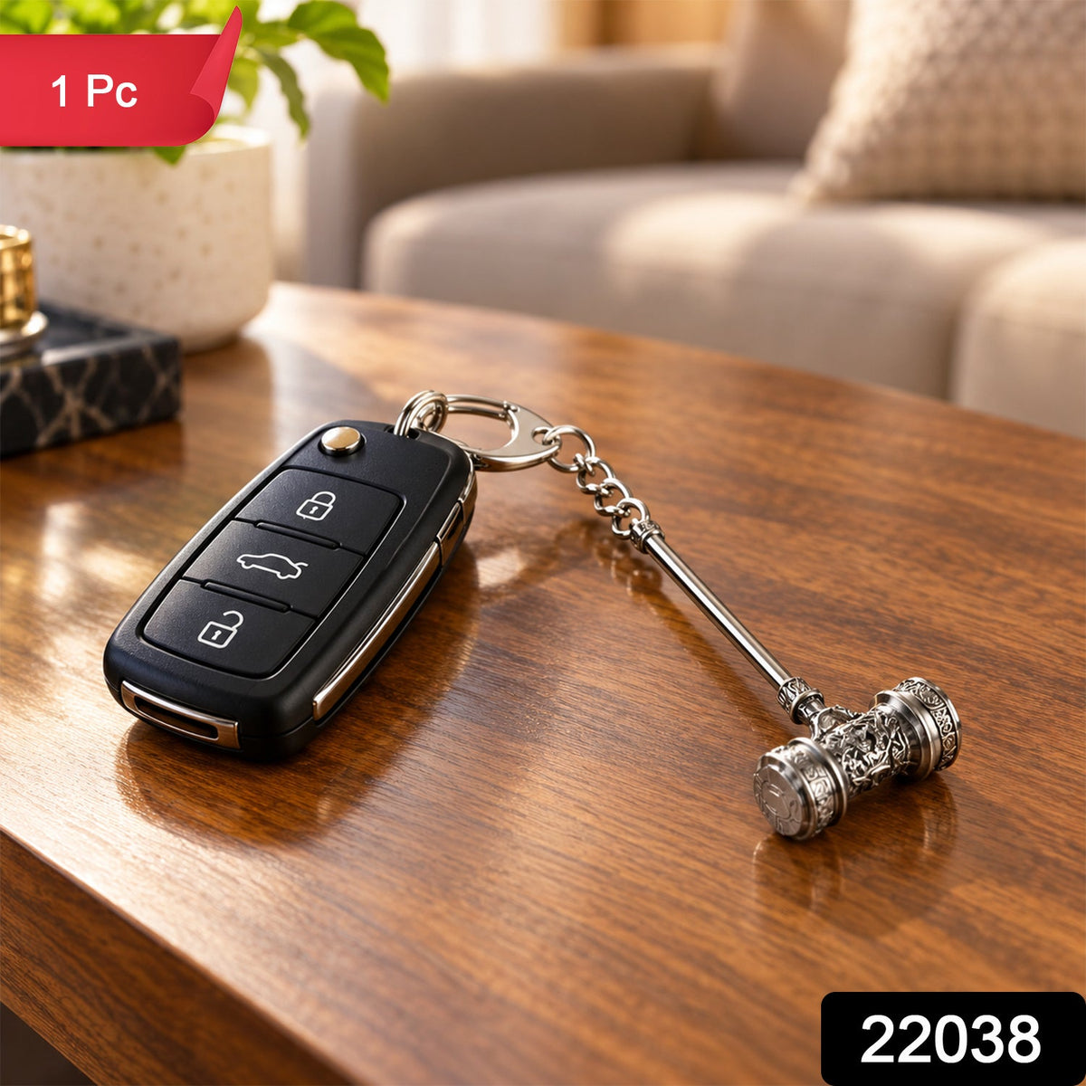 Silver-plated hammer keychain attached to a black car remote, resting on a polished wooden table. A green plant and – view 2