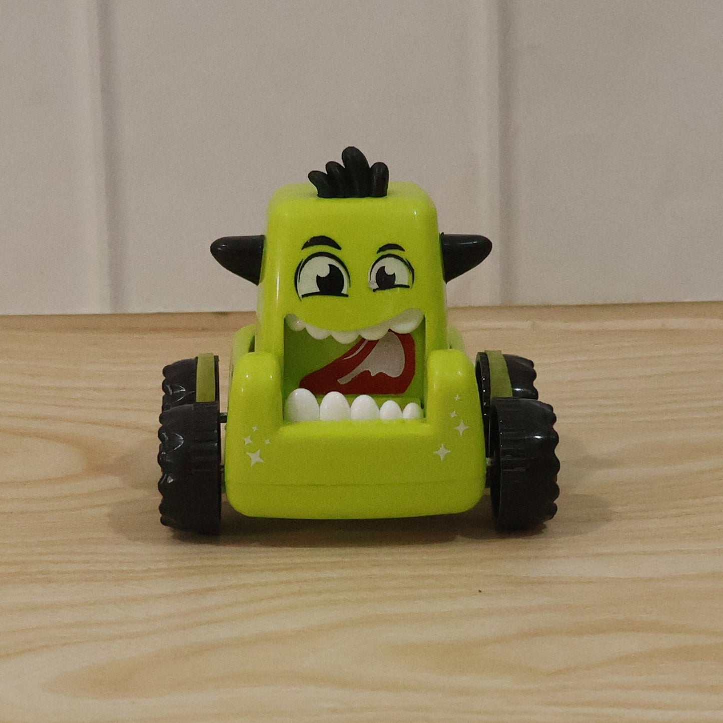 Child playing with a green cartoon monster car toy outdoors