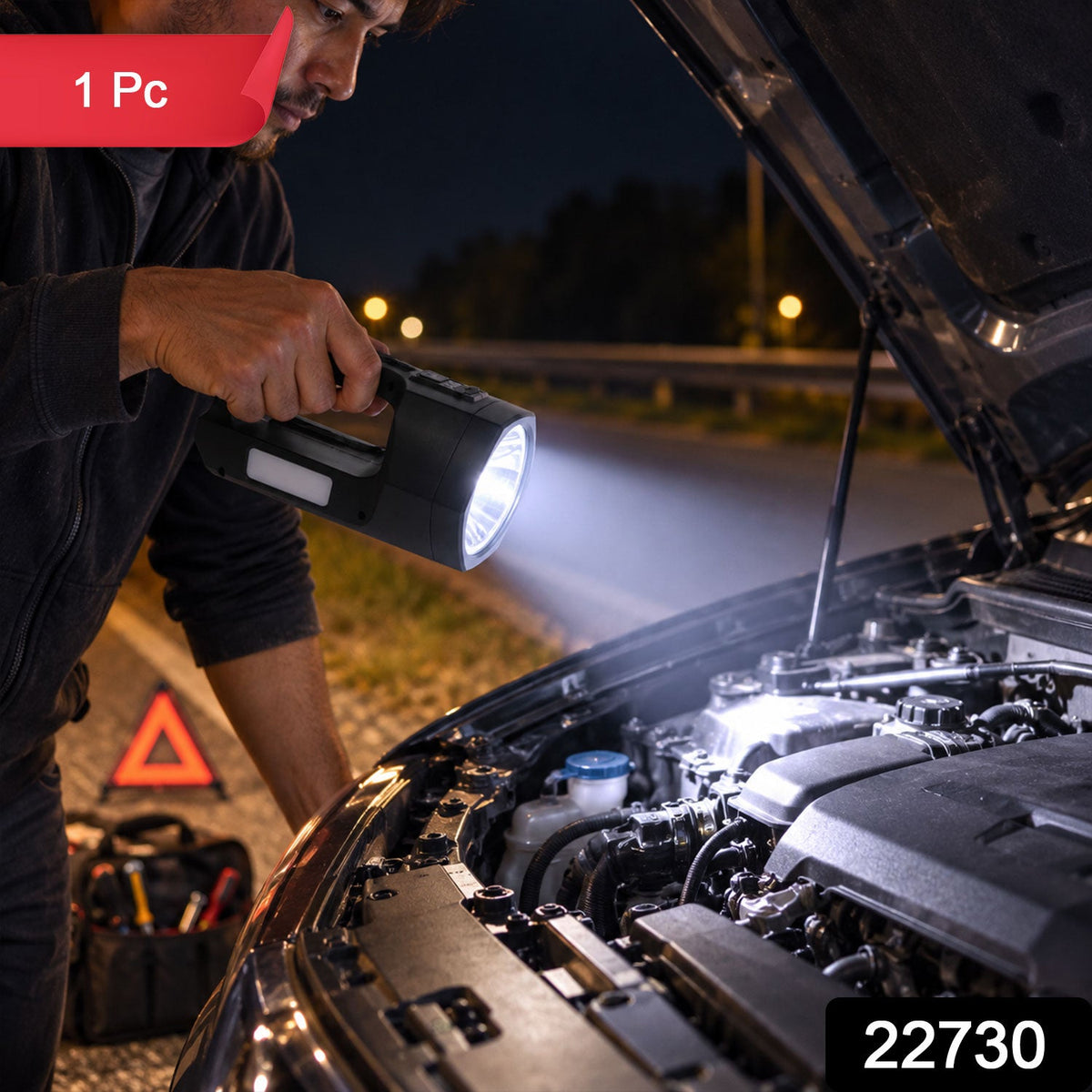 A person holds a dark-colored torch, illuminating a car engine on a dark road with an emergency triangle nearby.