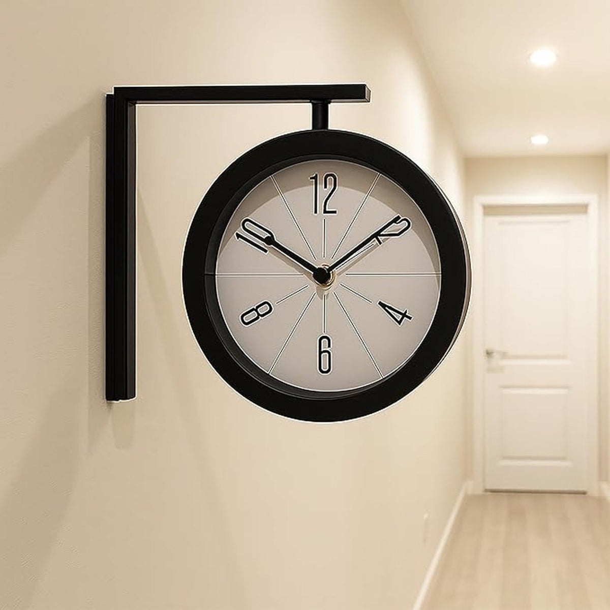 A black double-sided wall clock with a white face and black numbers is mounted on a light beige wall in a hallway with a