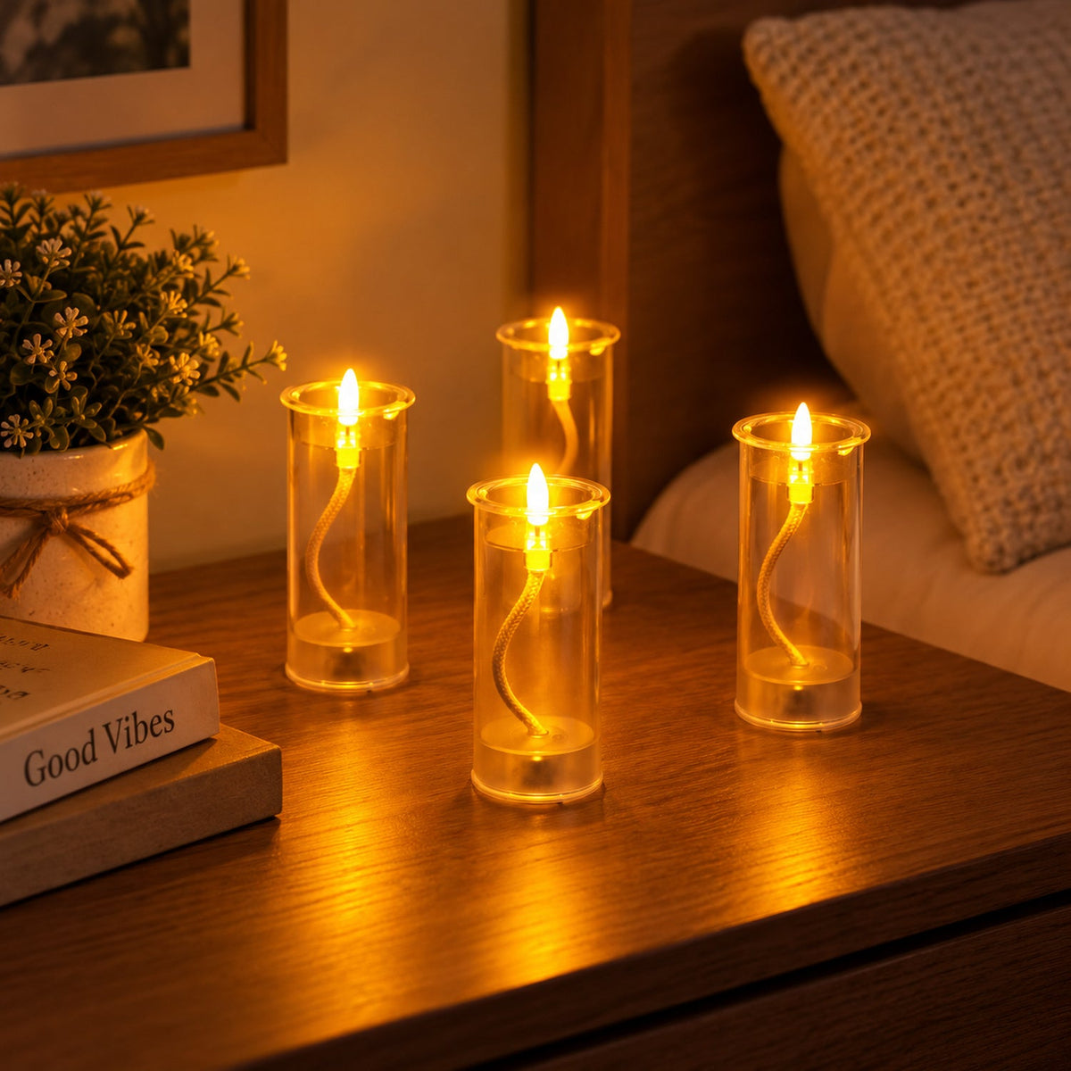 Four LED swing candles illuminate a wooden bedside table, next to a small potted plant and a book titled "Good Vibes".