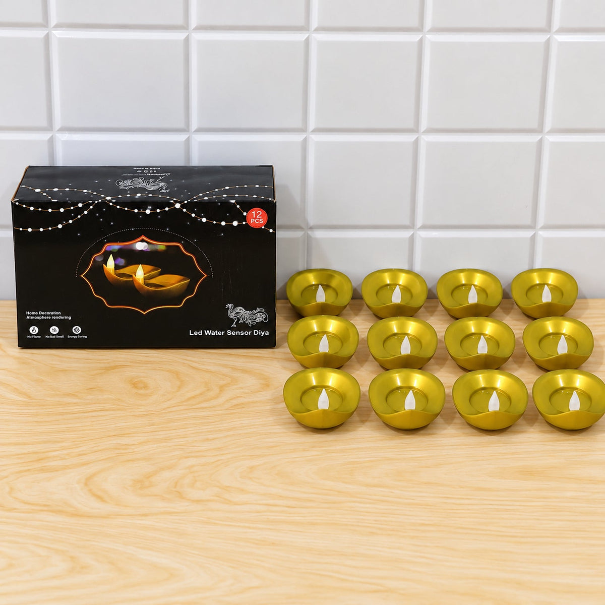 A black product box sits next to twelve golden LED diyas with white wicks on a wooden surface.