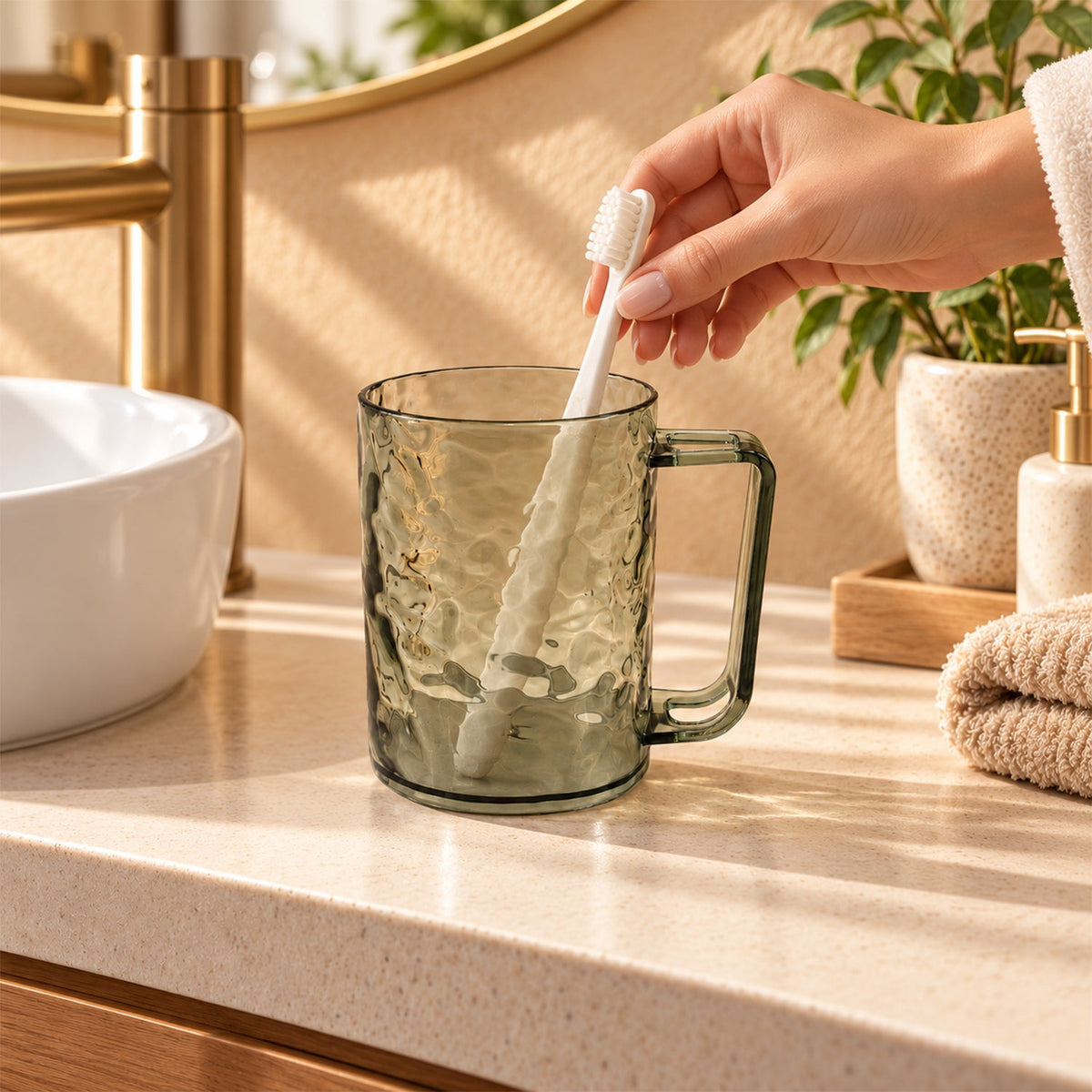 A hand placing a white toothbrush into a dark grey textured plastic mug on a bathroom counter.