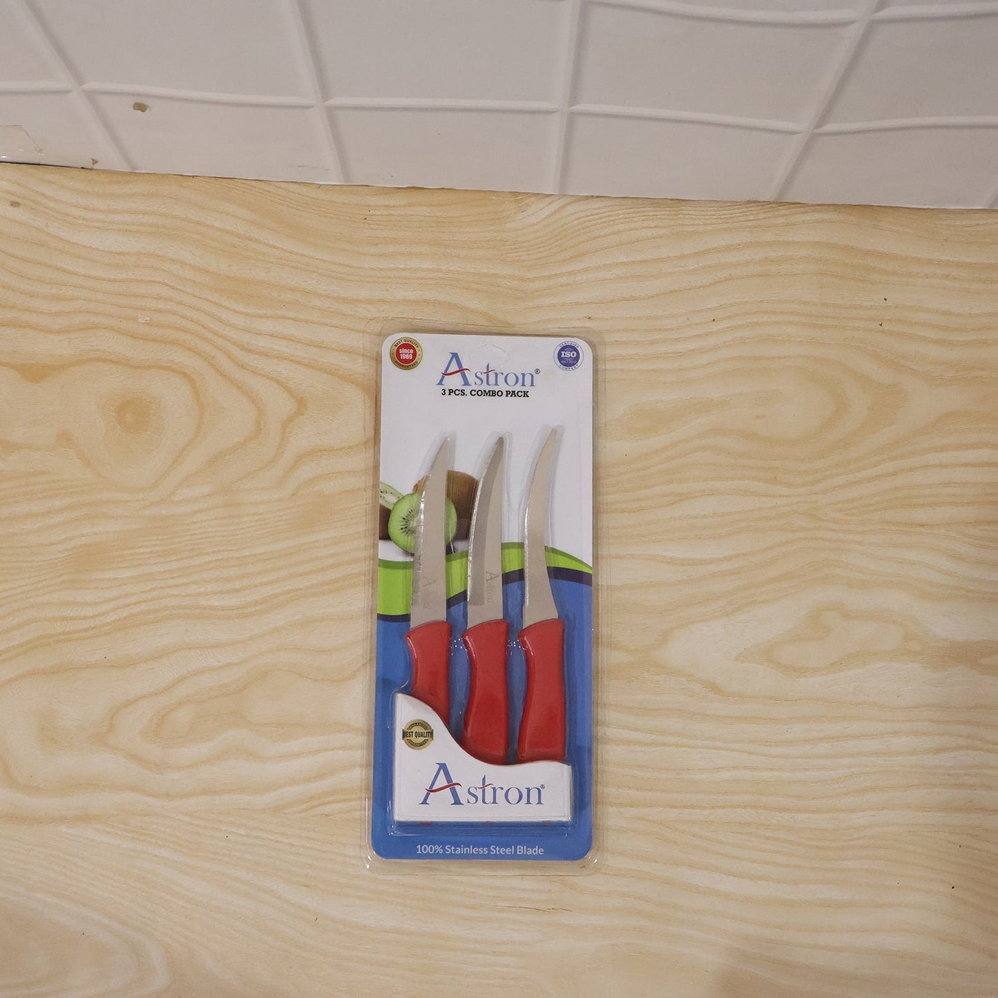 Stainless steel knife peeling an apple on a wooden cutting board