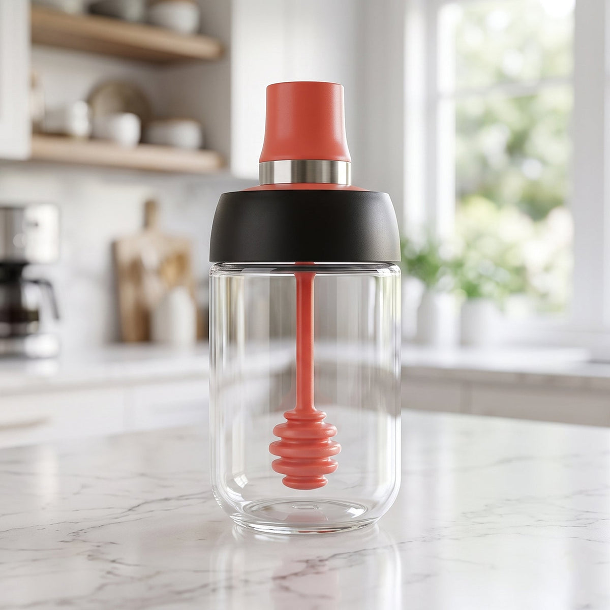 A clear glass dispenser with a red silicone dipper and black and red lid stands on a marble kitchen counter.