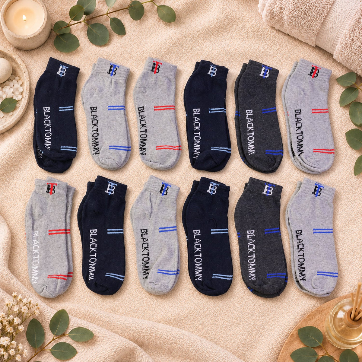 Twelve pairs of ankle socks in various colors and stripe combinations are arranged on a textured blanket.
