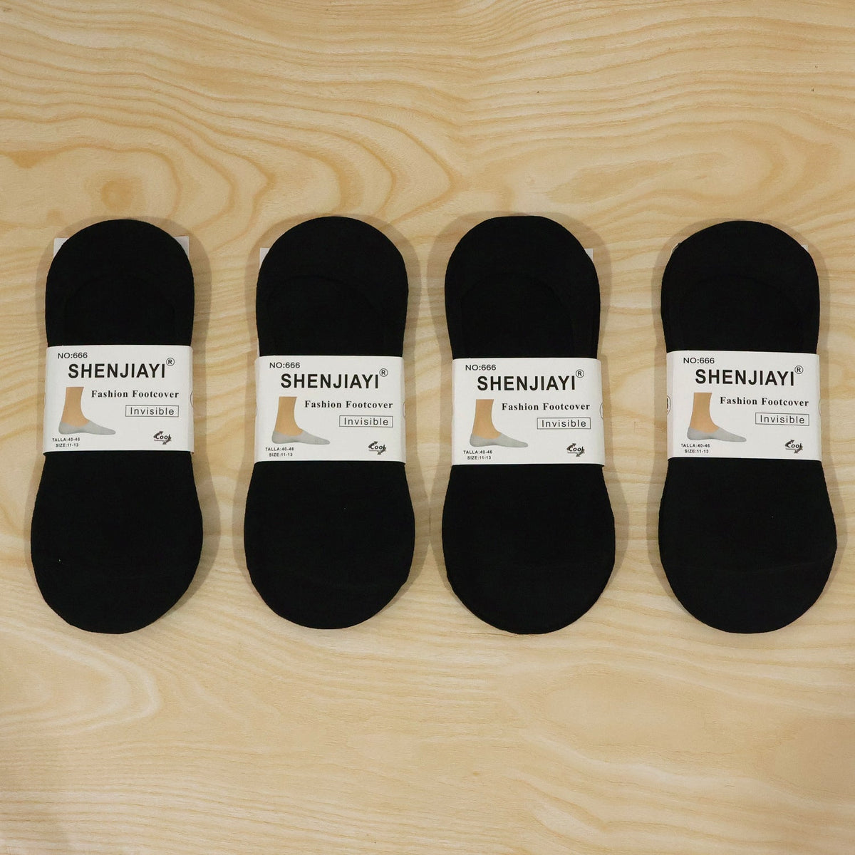 Four individually packaged black low-cut socks from the brand Shenjiayi, laid on a wooden surface.