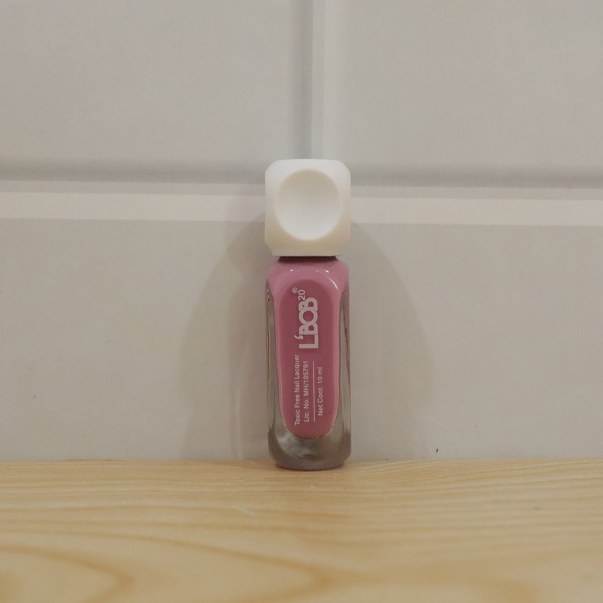 Pink Nude Colour Nail Polish bottle with painted nails in background
