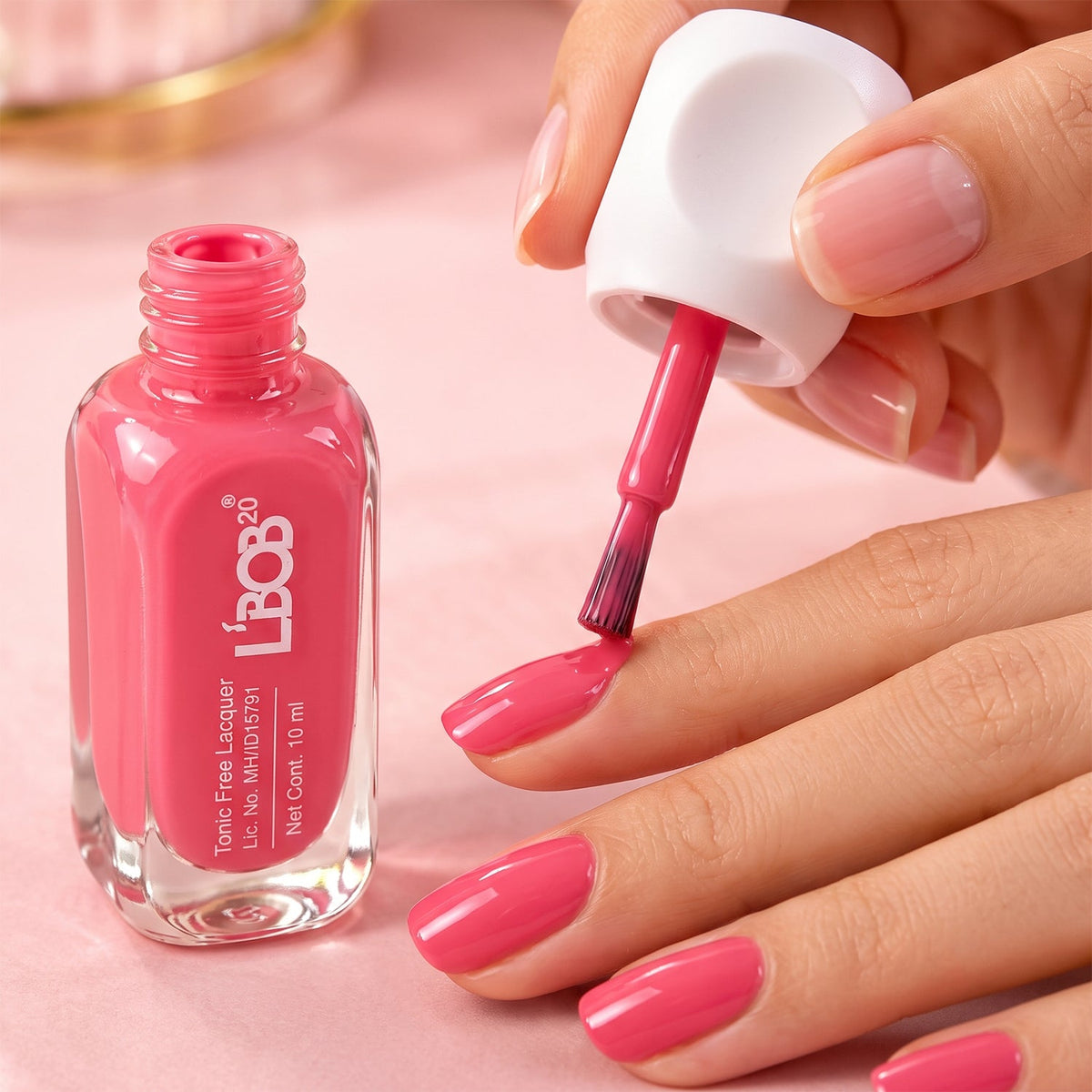 A person applies bright pink nail polish to their fingernails with a brush from an open bottle.