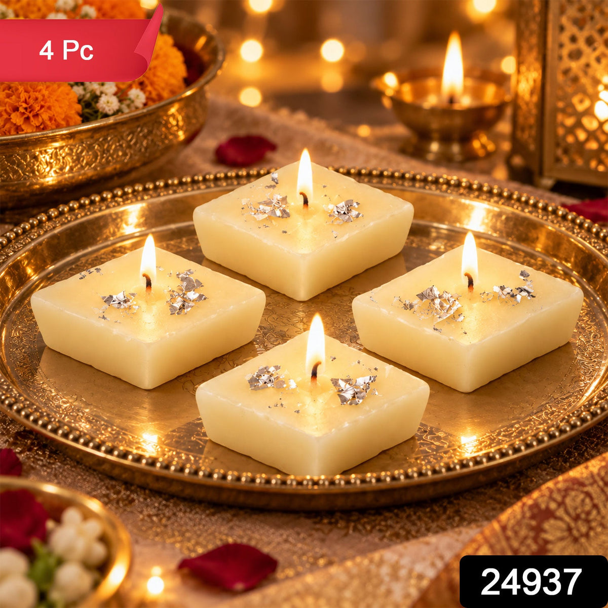 Four unlit diamond-shaped cream candles with silver foil accents on a gold ornate tray, with a blurred background of lights