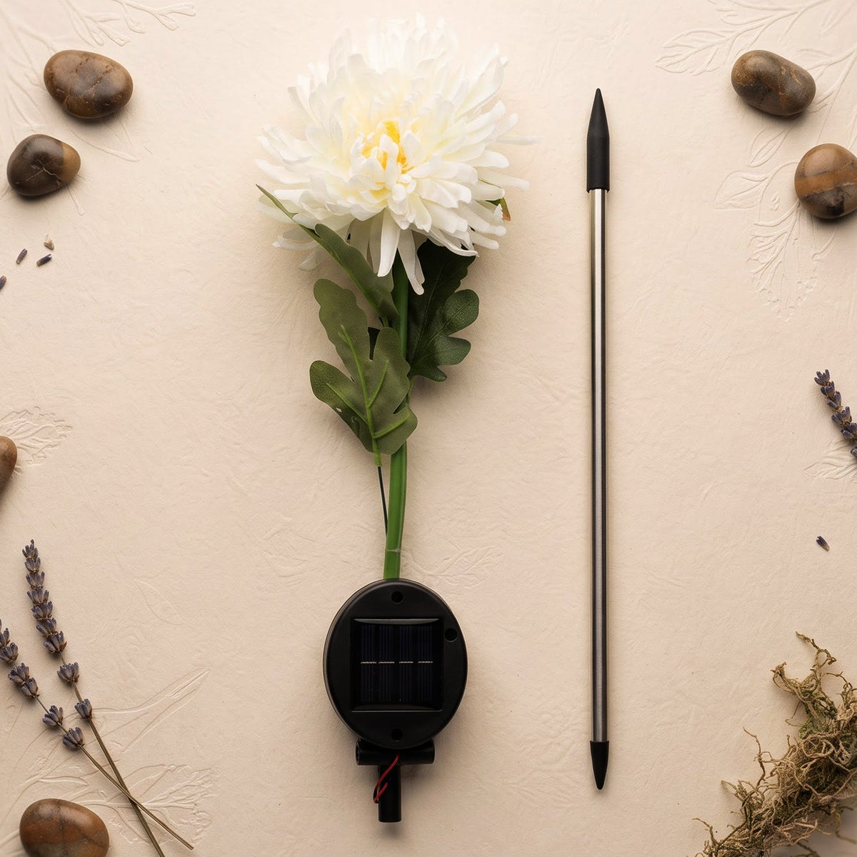 The disassembled white chrysanthemum solar light components laid out on a textured beige surface with decorative stones and