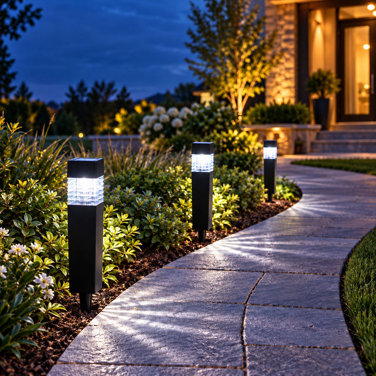 Three black solar lights illuminate a curved stone pathway next to green foliage at dusk.