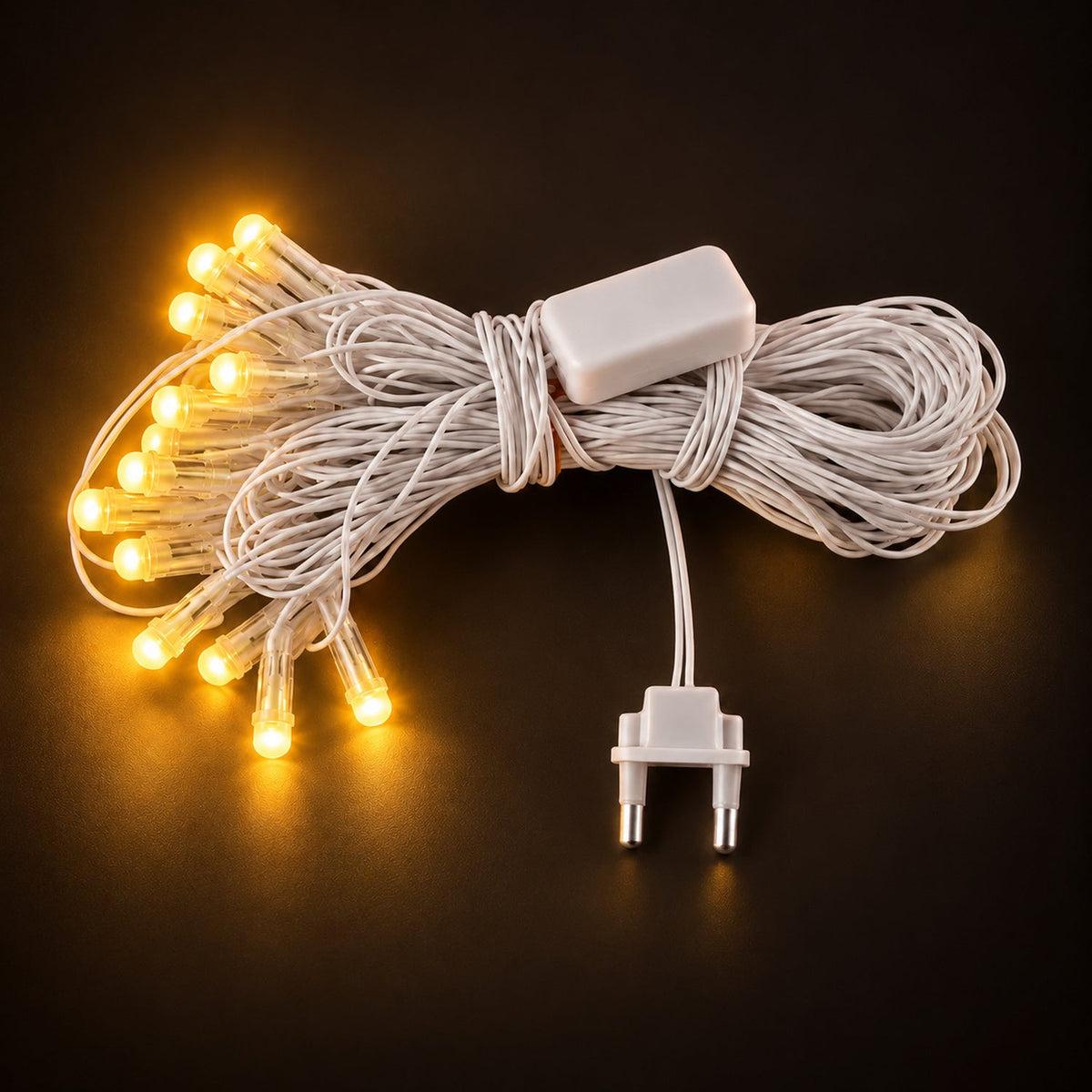 A coiled white LED string light set with a power adapter and two-pin plug, glowing warm yellow on a dark surface.