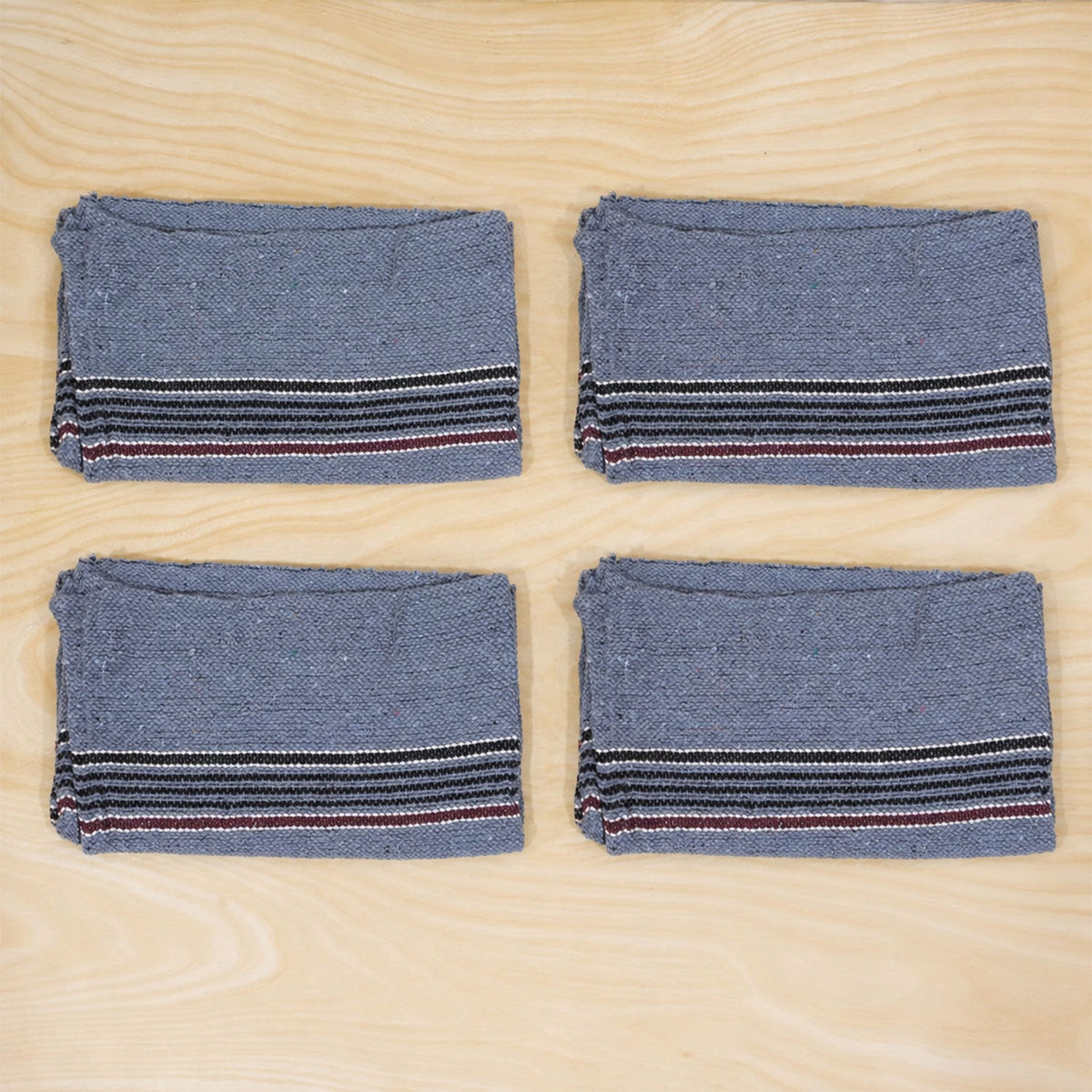 Four folded blue cleaning cloths with striped borders are neatly arranged on a wooden surface.