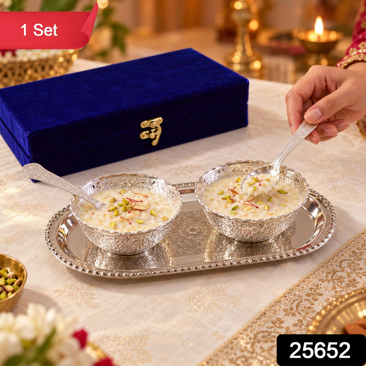 A hand holds a silver spoon above a bowl of dessert on an ornate silver tray, next to a blue velvet box. – view 2
