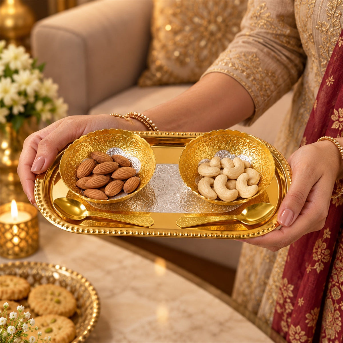 A person holding a golden tray with two golden bowls filled with almonds and cashews, and two golden spoons.