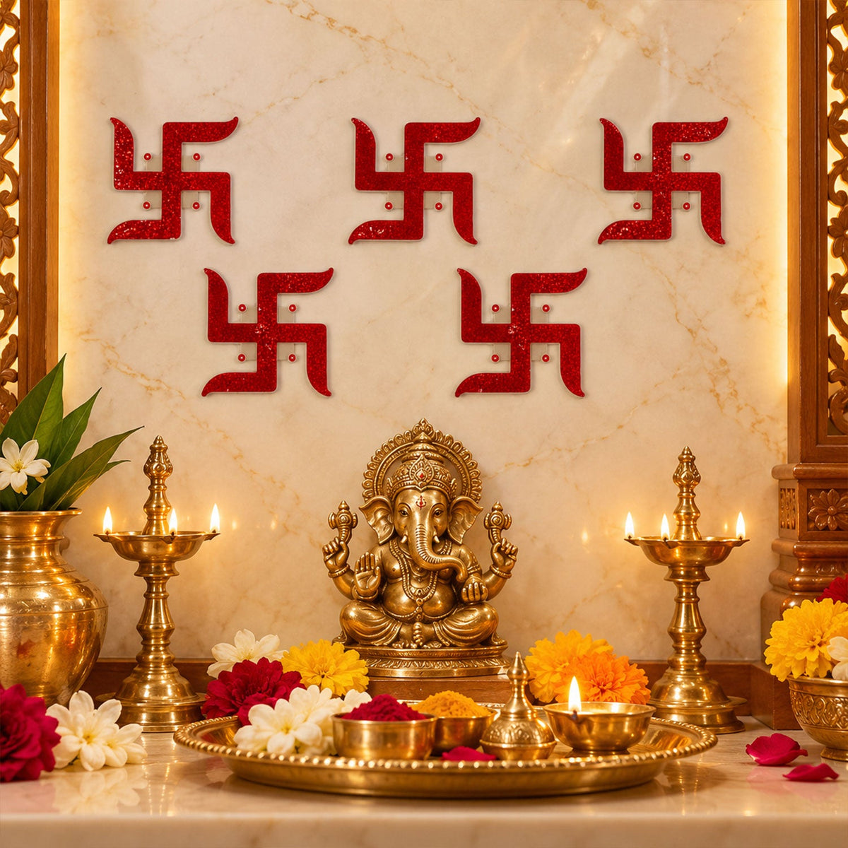 Five red glitter swastik stickers decorate a light-colored wall above a brass Ganesha idol and lit oil lamps.