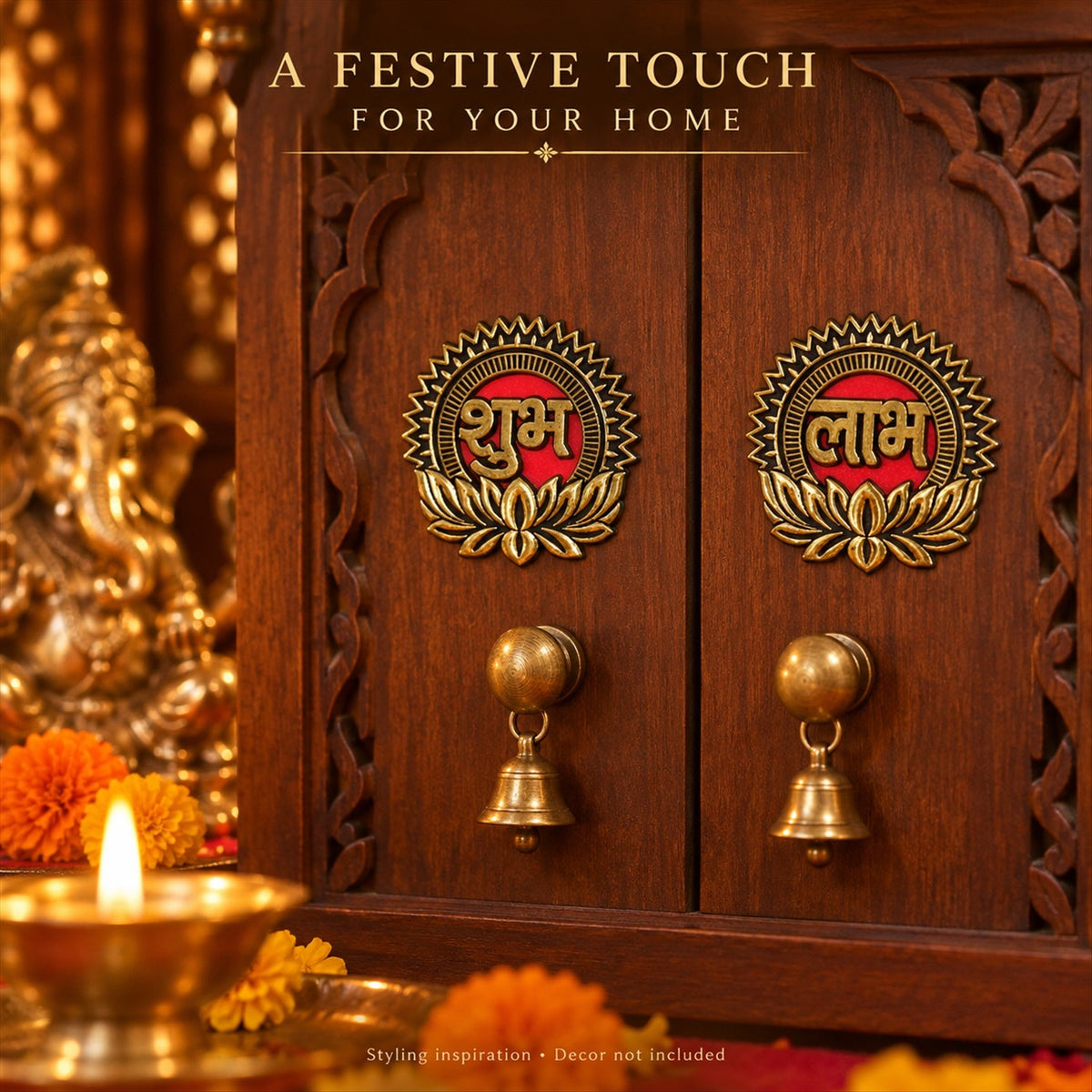 Two gold and red Shubh Labh stickers on a small wooden cabinet, with decorative bells and a blurred Ganesha idol.