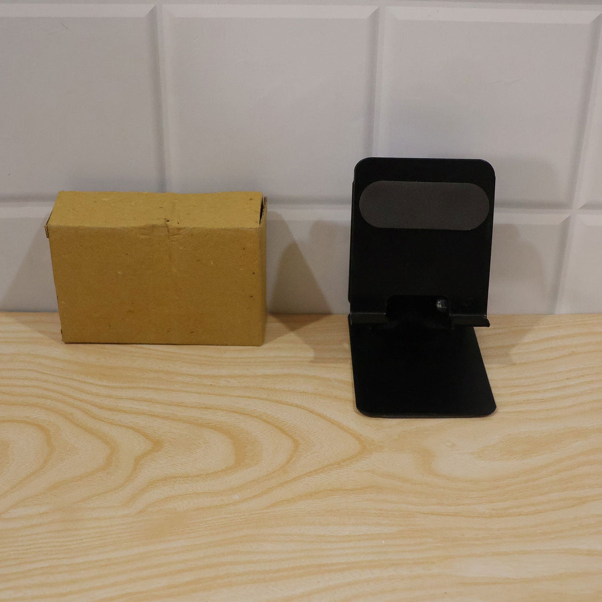 Foldable metal mobile phone stand on a desk with a laptop