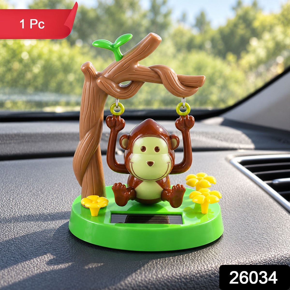 A solar-powered monkey figurine on a green base with a tree and yellow flowers sits on a car dashboard.