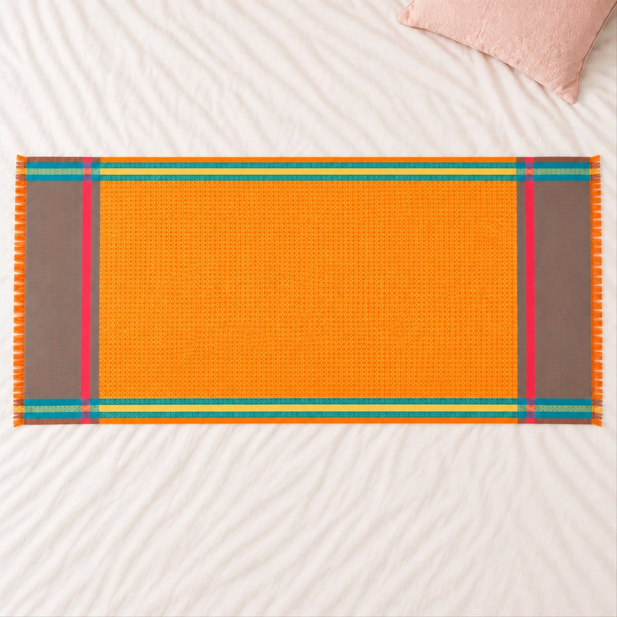 An orange shawl with teal, yellow, and pink striped borders and fringe, lying on a white textured surface.