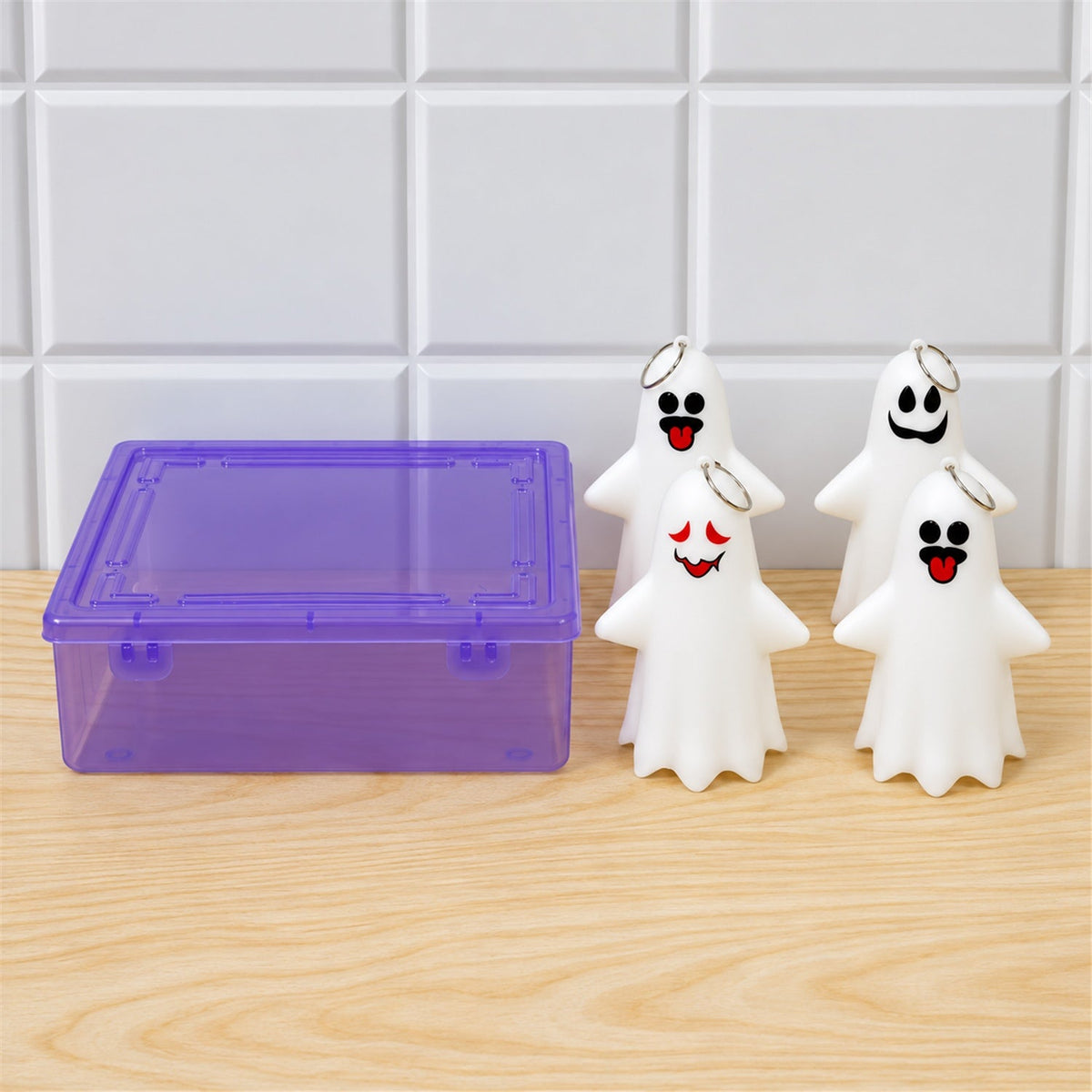 Four white ghost figures with varied faces and a purple transparent storage box are on a wooden surface.