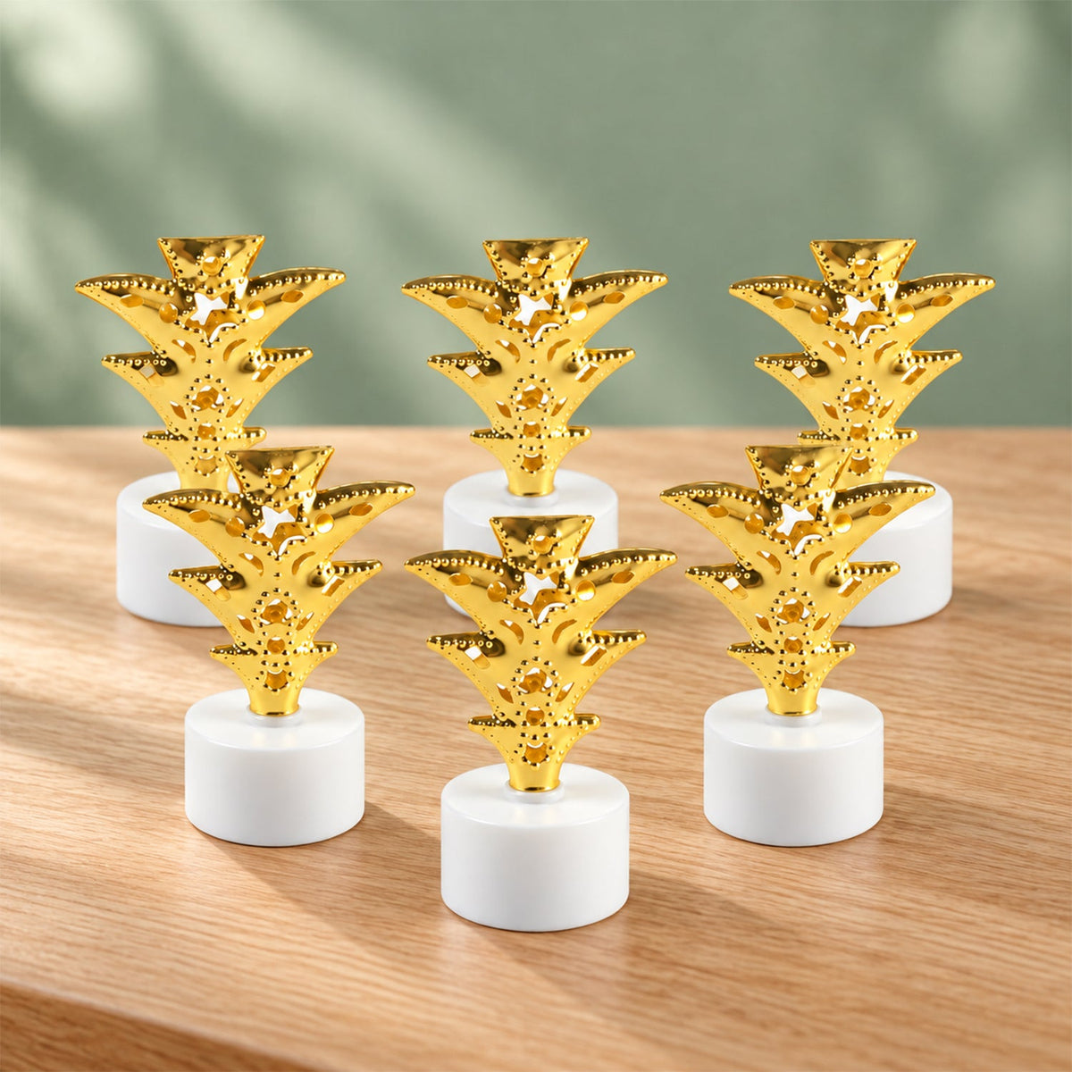 Six golden pineapple LED tealights arranged neatly on a light wooden table.
