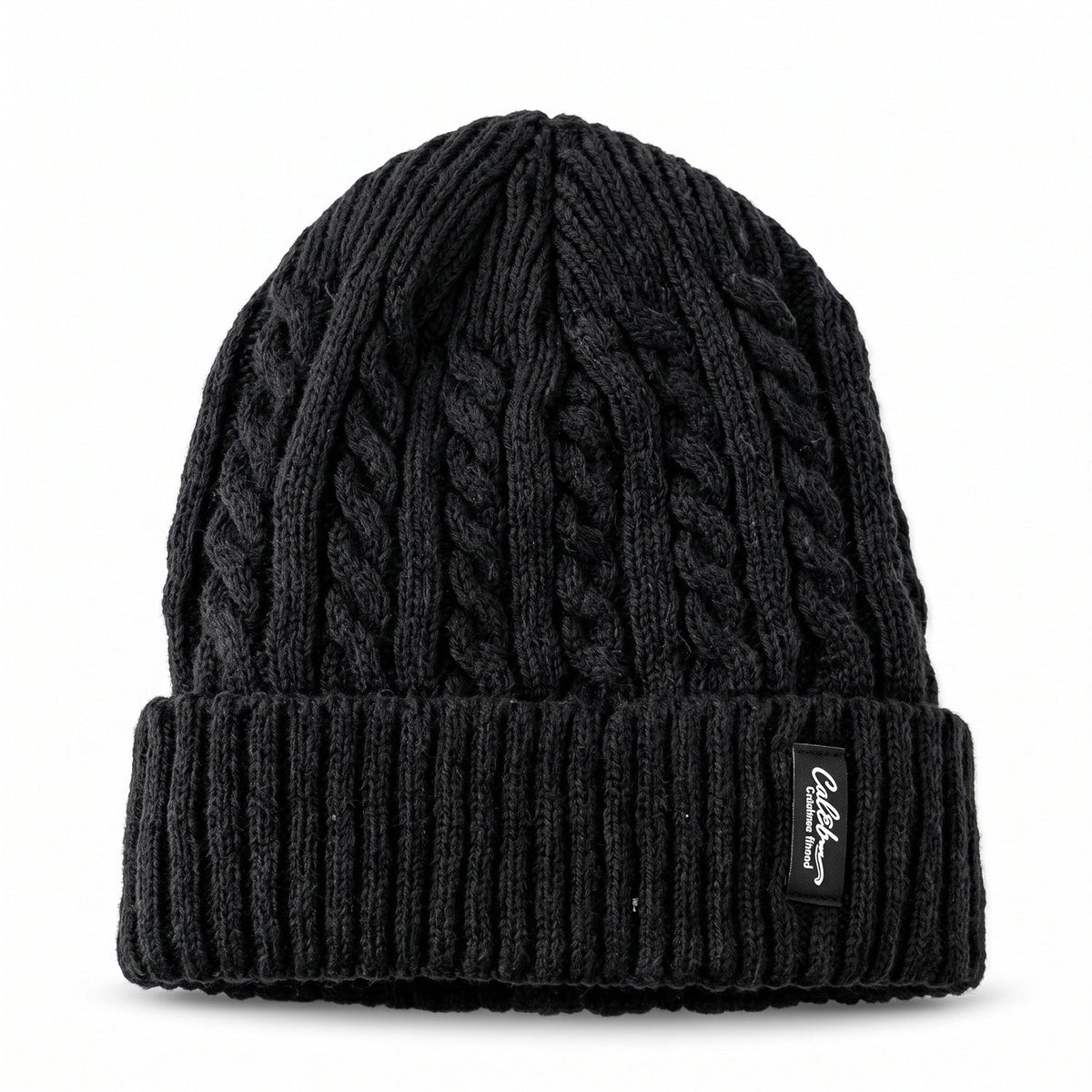 A black cable knit beanie with a textured crown and ribbed folded cuff, featuring a rectangular brand tag.