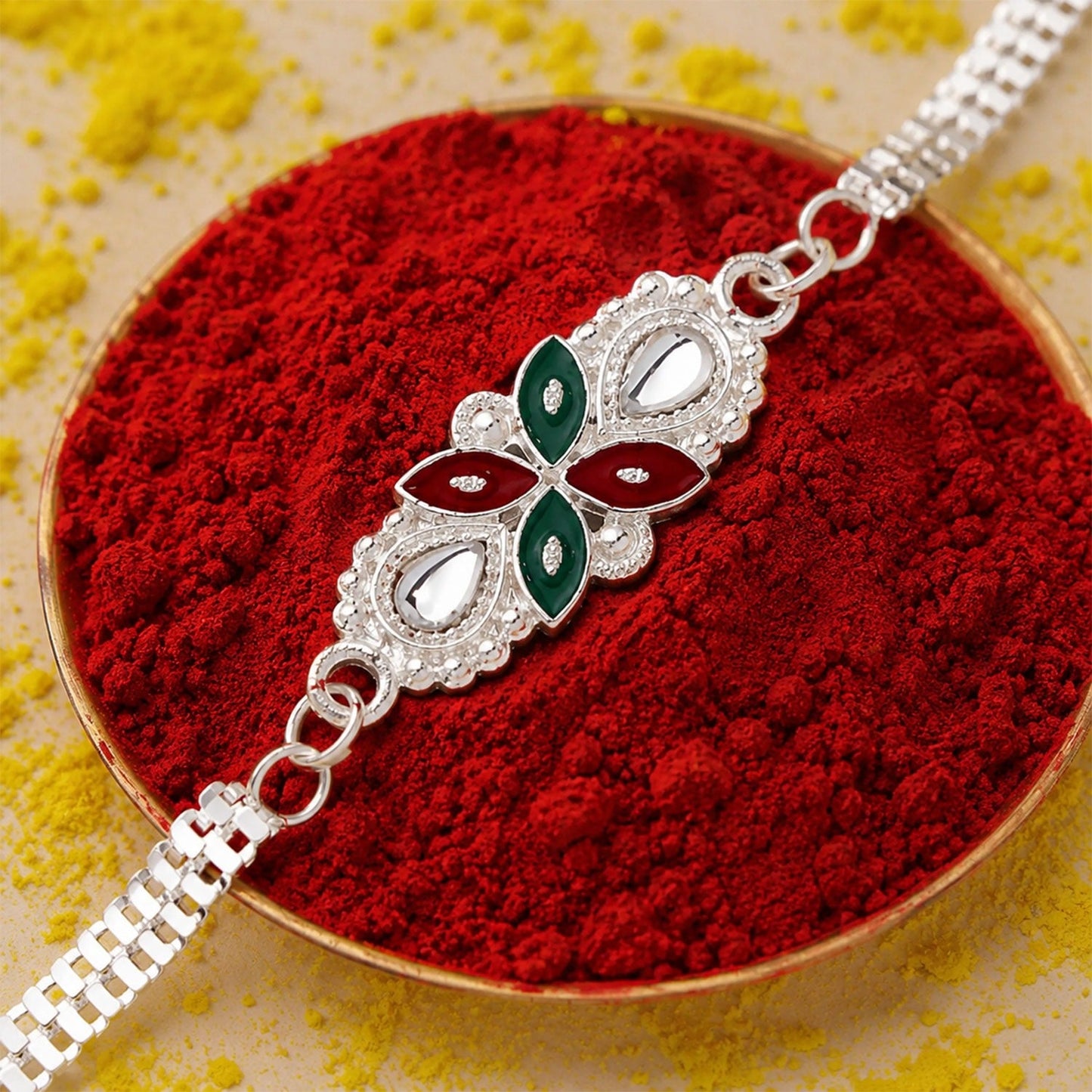 Elegant Floral Rakhi with intricate red and green enamel design on a white background.