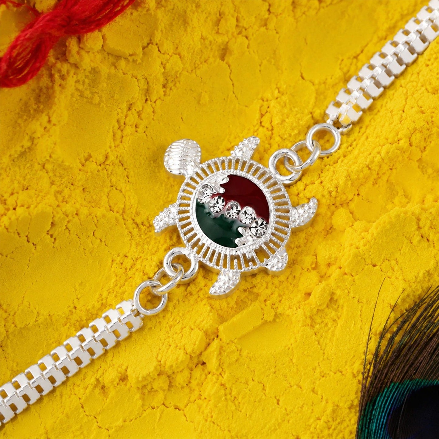 Turtle Rakhi with red and green enamel on a silver metal chain symbolizing protection and good fortune.