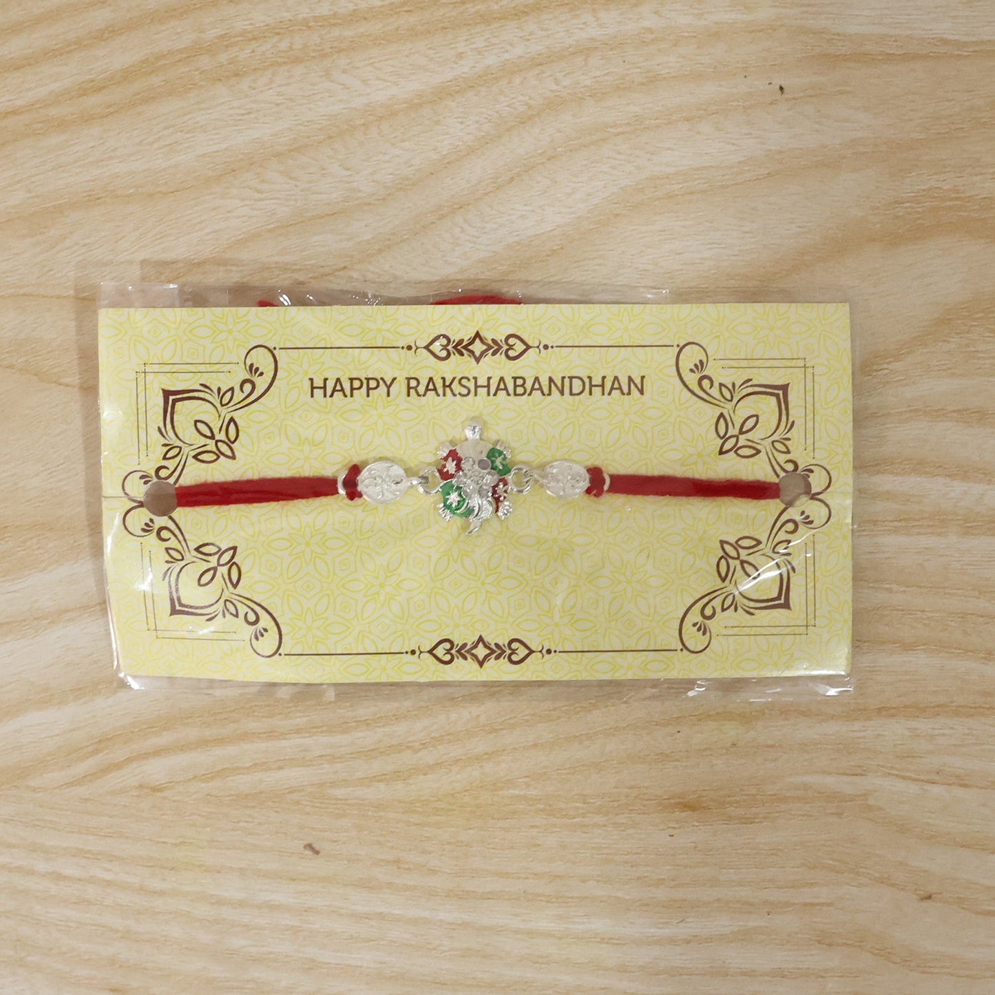 Overhead shot of Turtle Rakhi featuring green enamel and crystals.