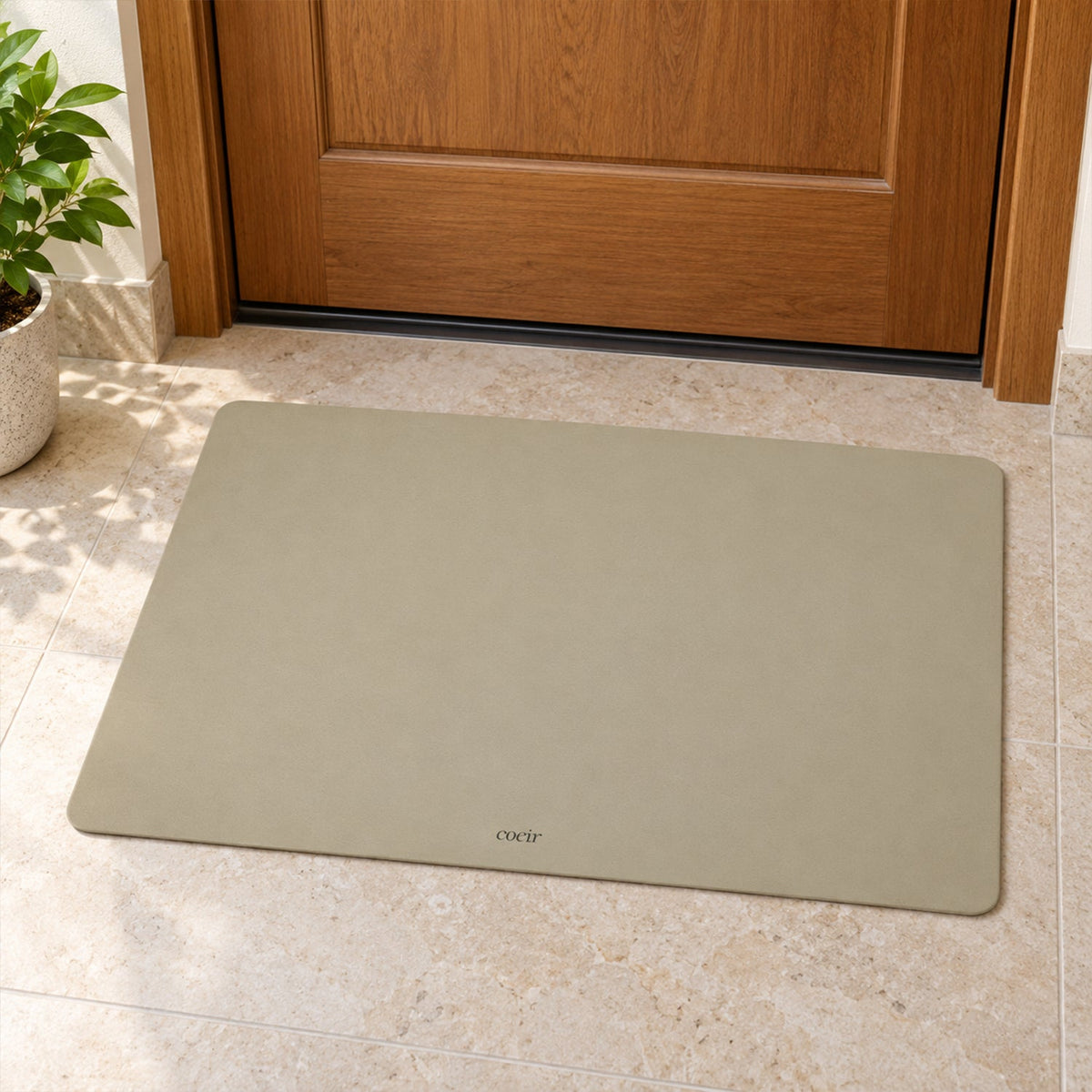 A light beige rectangular floor mat rests on light-colored tiles in front of a wooden door.