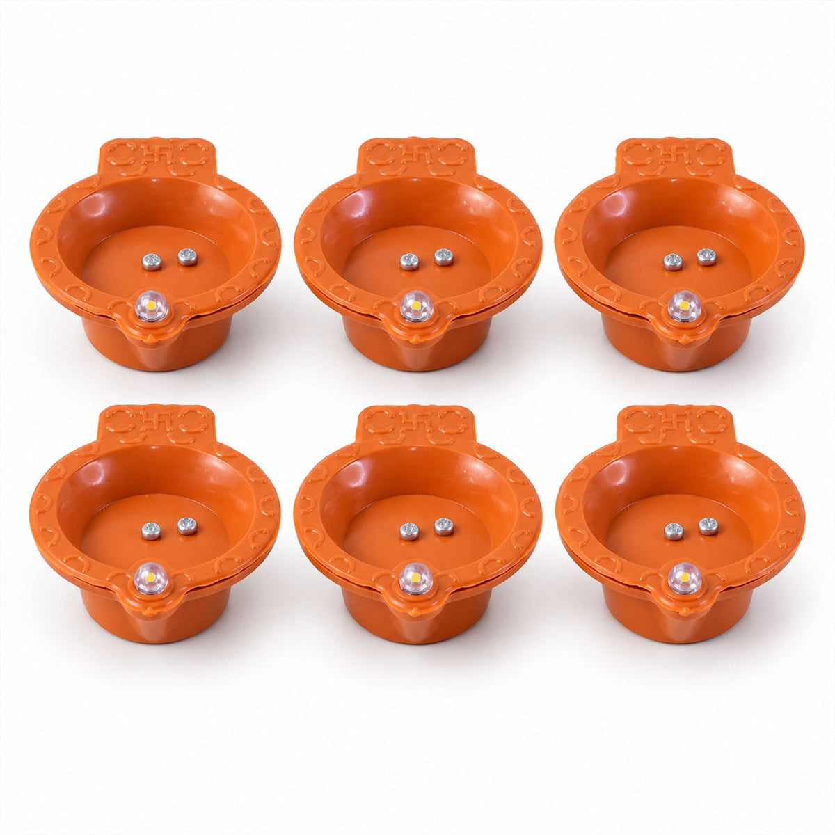 Six identical orange diyas, each with two silver sensors and a clear LED lens, are arranged on a white surface.