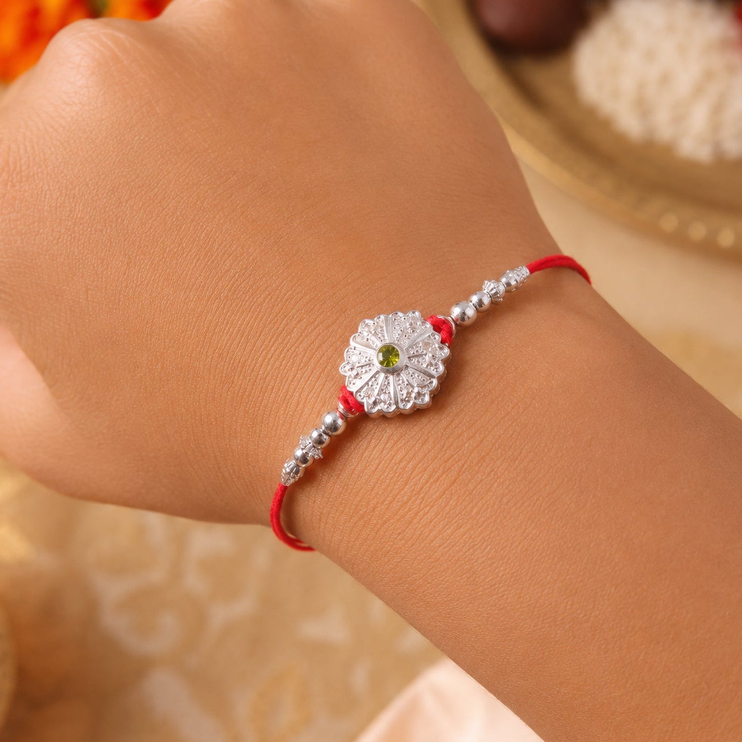 Beautiful traditional Rakhi with green stone centerpiece and detailed beads