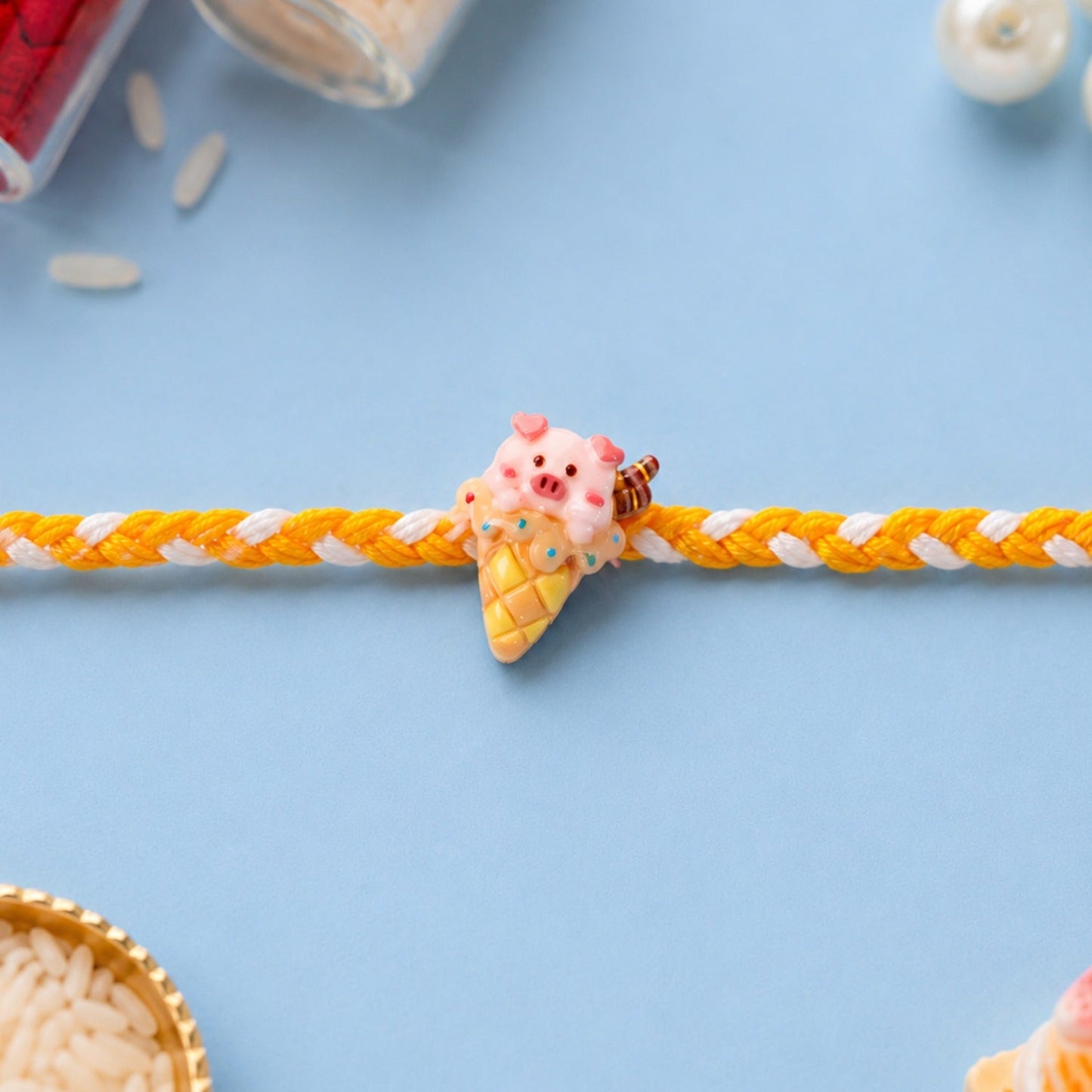 Adorable Cute Pig Rakhi with ice cream motif on a decorative background.