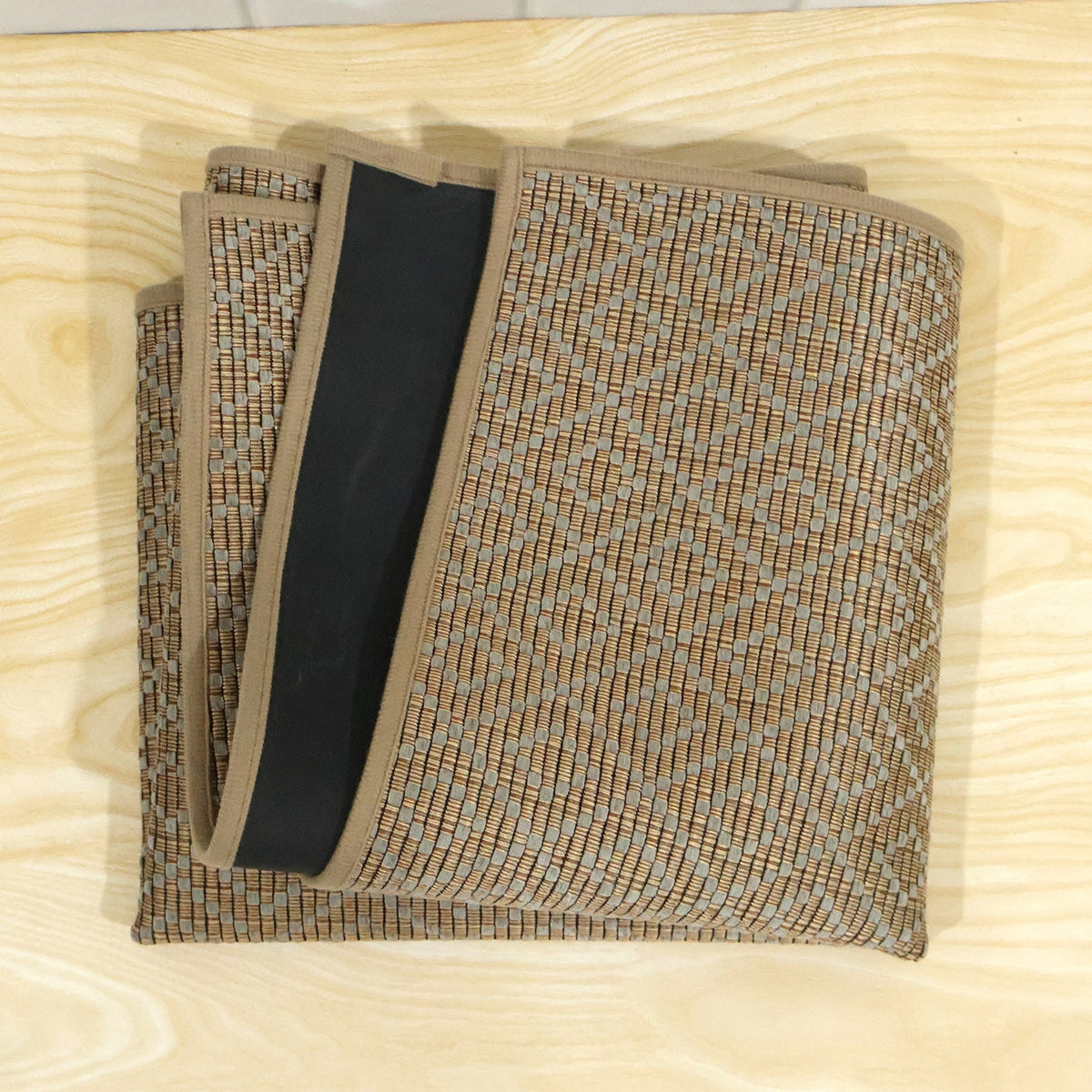 The brown diamond pattern runner mat is folded neatly, revealing its black backing and woven texture.