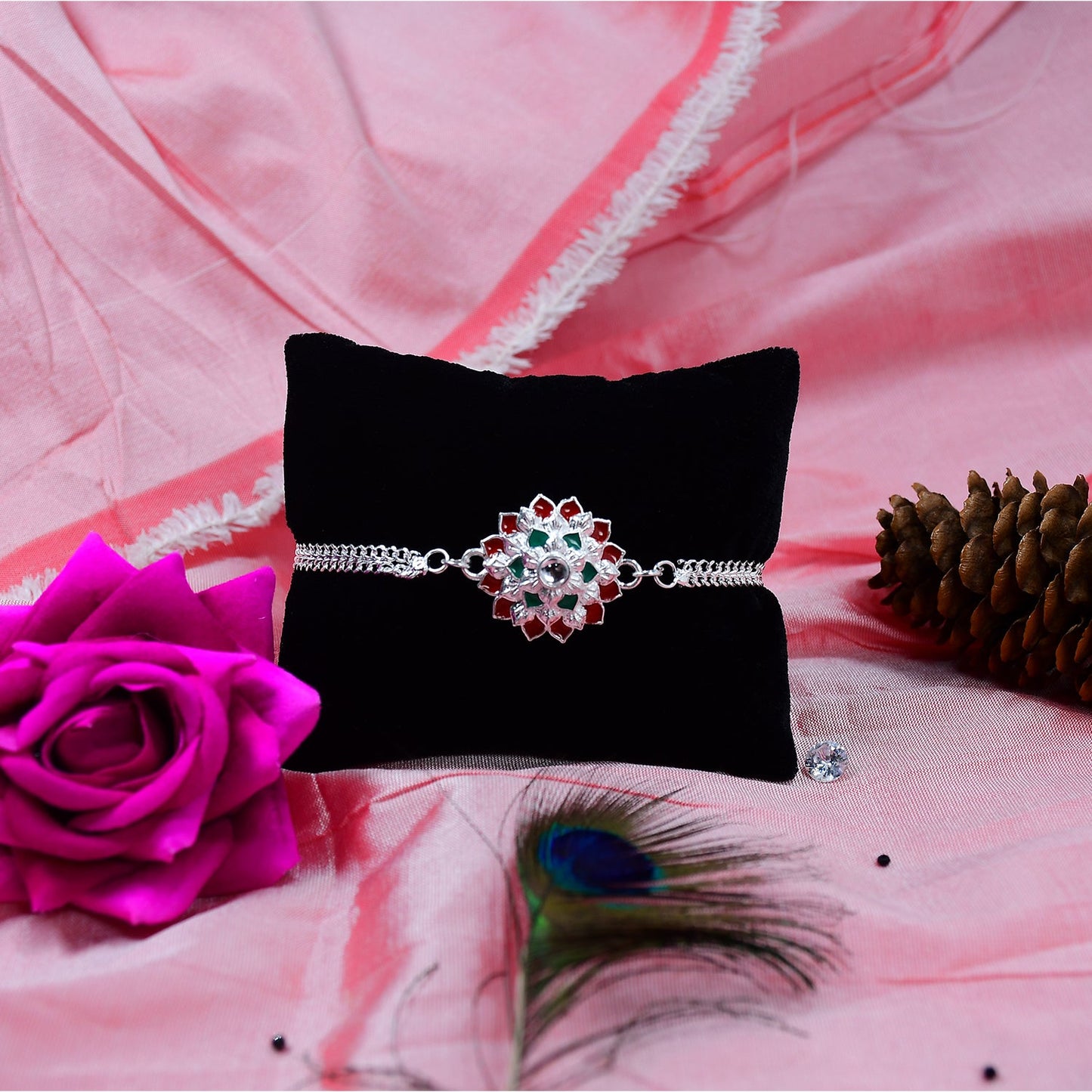 Close-up of handcrafted Silver Chain Rakhi, highlighting red and green details.