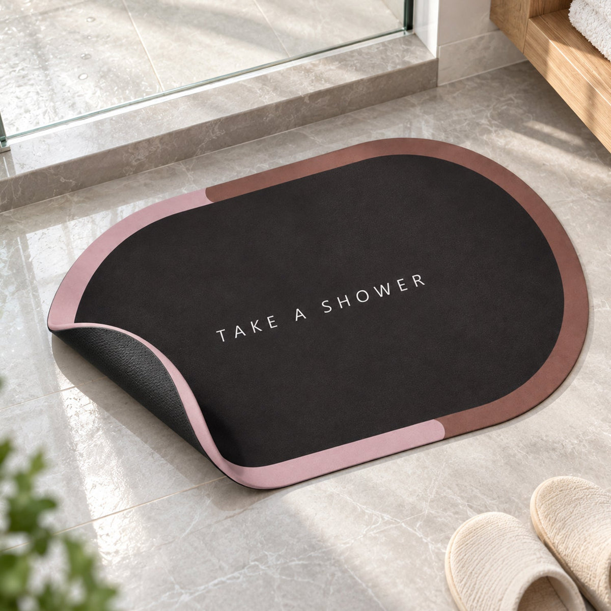 A dark oval bath mat with a pink and brown border is partially lifted, revealing its black underside on a tiled floor.